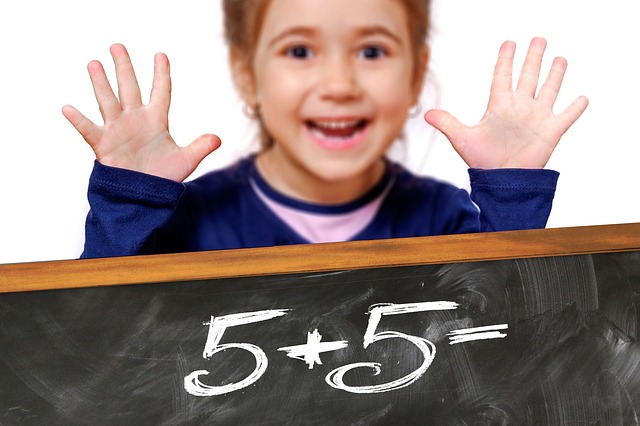 黒板に書かれた5+5＝と両手を広げて笑顔の少女