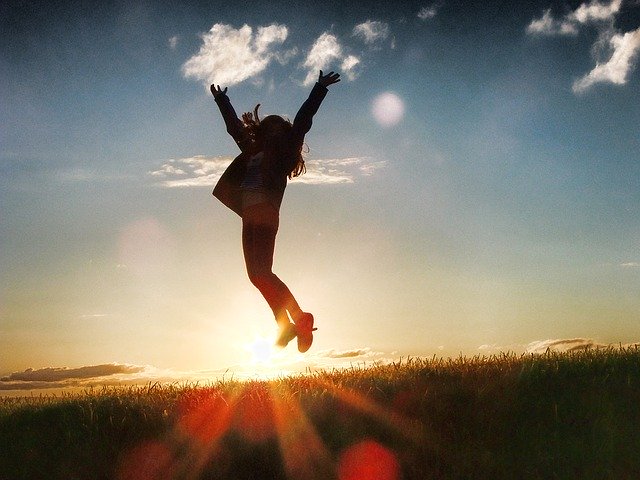夕陽の前で歓喜のジャンプをする女性